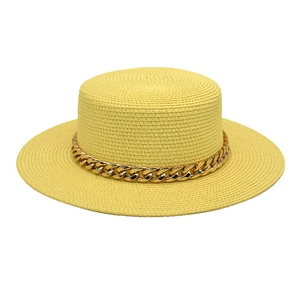 Détail chapeau de paille jaune à sommet plat avec grosse chaîne dorée en acrylique