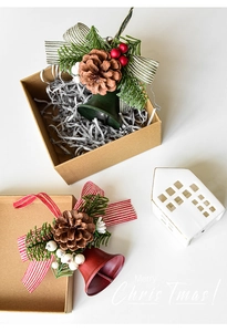 Close-up of festive red and green metal bells with pine cones and bows in a gift box