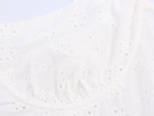 Detail of white midi dress showing intricate Broderie Anglaise embroidery and floral patterns