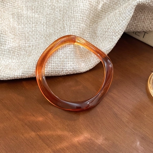 Detail of amber translucent resin bracelet with artistic swirling on a wooden surface
