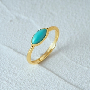 Macro shot of turquoise leaf ring with gold band on white stone texture background