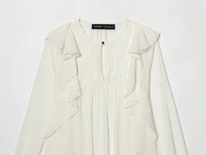 Detailed view of pearl white shirt featuring tiered ruffles and pleated front neckline