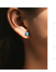 Close-up of s925 silver stud earring featuring a brilliant blue opal on a model's ear