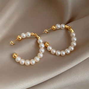 Elegant gold-plated pearl hoop earrings displayed on champagne silk fabric background