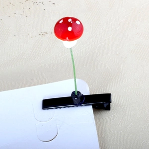 Close-up of red mushroom hair clip with white spots on a green metal stalk detail