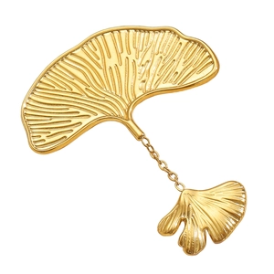 Macro detail of golden ginkgo leaf brooch with fine texture and metal link chain