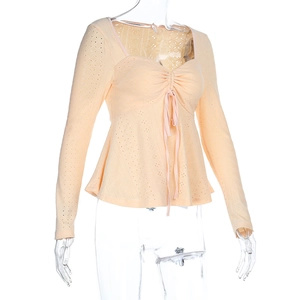 Detail of light orange knit top featuring V-neck, drawstring front, and eyelet texture