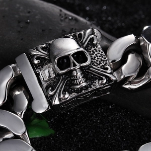 Dettaglio del bracciale con teschio d'argento e grossa catena groumette su pietre nere