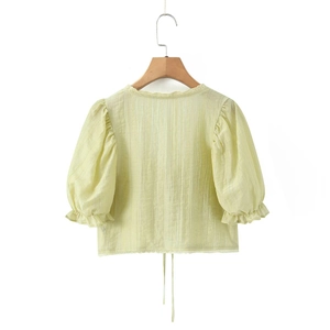 Détail du haut jaune clair à manches bouffantes et texture verticale sur cintre en bois