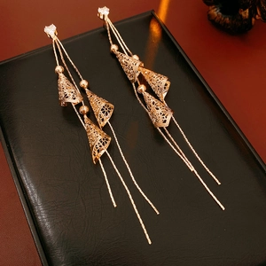 Détail de boucles d'oreilles pompons dorées avec maille conique et gemmes brillantes