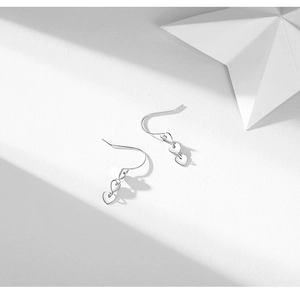 Elegant silver heart drop earrings with triple heart pendants in polished metal finish