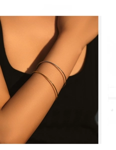 Detail showing minimalist gold and silver slim bangles stacked on a wrist with soft light