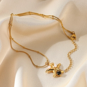 Detailed shot of starfish pendant with pearls and black gem on gold bead chain
