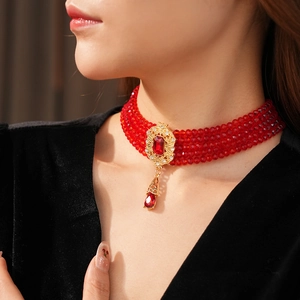 Close-up of vintage multi-strand red bead necklace with ornate gold-tone ruby pendant