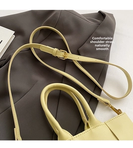 Dettaglio della texture in pelle giallo chiaro e tracolla della borsa a mano intrecciata
