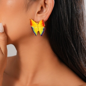 Macro detail of colorful enamel butterfly earring worn by a model with soft lighting