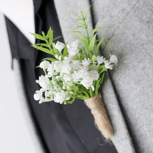 Artificial white baby breath boutonniere with green leaves on a grey wedding suit lapel