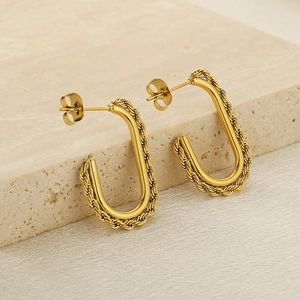 Detail showing golden U-shaped earrings with twisted rope texture and polished inner surface