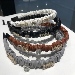 Détail de serre-têtes en cuir froncé avec lettres en cristal et strass en quatre tons