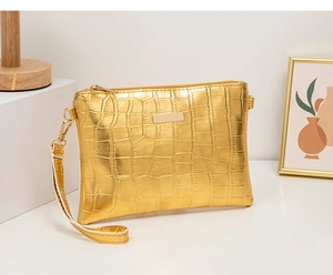 Detail of gold crocodile embossed leather clutch with zipper closure and wristlet strap
