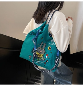 Detail of teal canvas tote bag with drawstring straps and cute rabbit illustrations