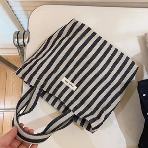 Detail of striped canvas tote bag with a woven simple wish label and dual handles