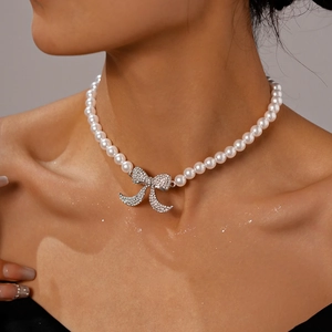 Dettaglio girocollo di perle vintage con pendente a fiocco in strass indossato dal modello