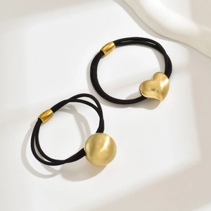 Close-up of minimalist hair ties with vintage gold heart and ball pendants