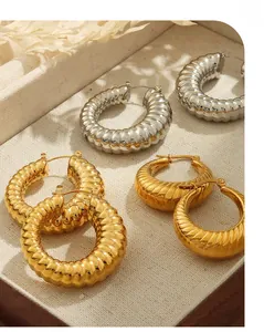 Dettaglio di orecchini a cerchio a forma di U in oro e argento con trama a costine