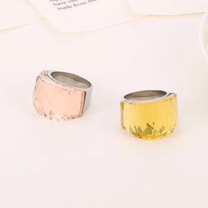 Titanium steel rings with pink and yellow translucent crystal gems on a white background