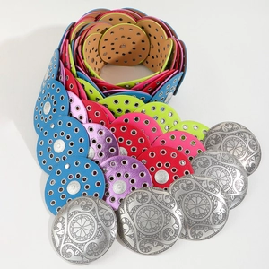 Macro detail of colorful leather disc belts with ornate silver floral engraved buckles