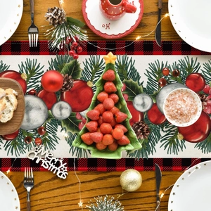 Close-up of Christmas table runner with pine patterns and red plaid borders on a wooden table