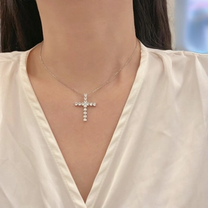 Close-up of a silver cross pendant with sparkling teardrop-shaped cubic zirconia crystals