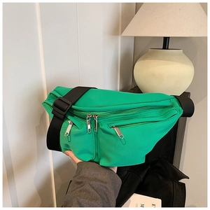Detail of bright green nylon crossbody bag showing multiple silver zippers and sturdy strap