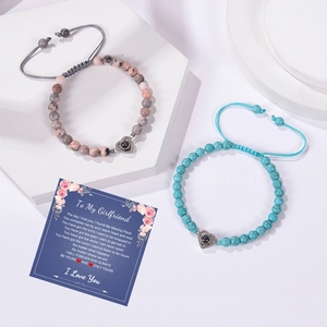 Gros plan de deux bracelets en perles avec pendentifs de projection sur une carte cadeau