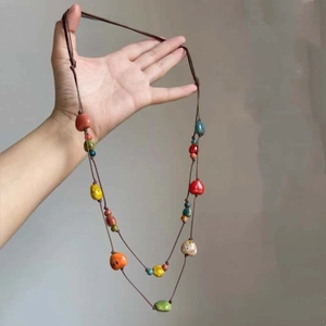 Detail of bohemian long beaded necklace with multi-color resin beads and woven cord chain