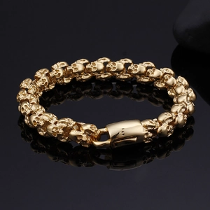 Detailed macro shot of golden stainless steel skull links on a reflective black surface