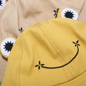 Detailed close-up of yellow and beige cotton frog fisherman hats with embroidery