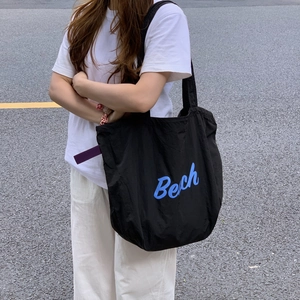 Detail view of a black canvas tote bag featuring blue letter print and drawstring closure
