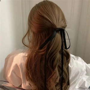 Elegant black long ribbon hair tie showing soft silk texture tied in a stylish bow knot