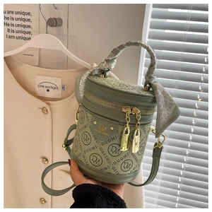 Detail of green cylinder bucket bag with floral scarf handle and gold locks