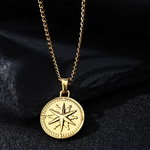 Détail du pendentif étoile boussole dorée sur chaîne torsadée posé sur pierre noire