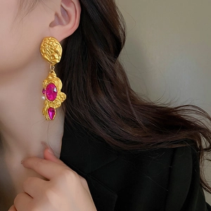 Detail of vintage baroque earrings with rose red stones and pearl on a model