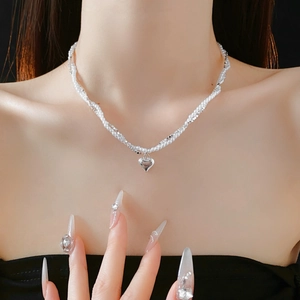 Detail shot of a double-layer pearl necklace with a 3D silver heart pendant on model
