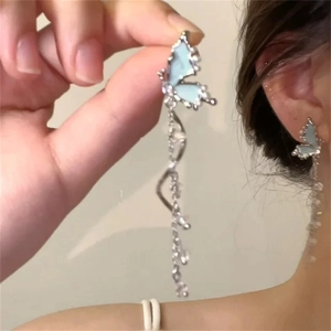 Detail of silver long tassel earrings featuring light blue butterfly wings and sparkling rhinestones