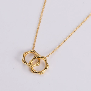 Macro detail of gold interlocking bamboo rings pendant on a fine link chain necklace