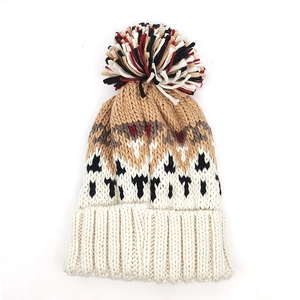 Detailed knit texture and colorful pompom on a warm winter hat with geometric patterns