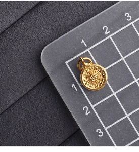 Macro detail of gold-plated round pendant with relief on a measuring mat