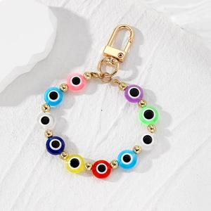 Colorful evil eye beaded keychain with gold metal clasp on a textured white background
