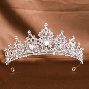 Detailed shot of a silver bridal crown with symmetric rhinestones on brown silk fabric